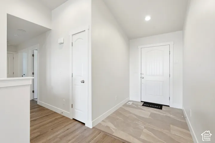 Entryway featuring a paneled door, recessed lighting, tile flooring, wood-finish flooring, and white trim