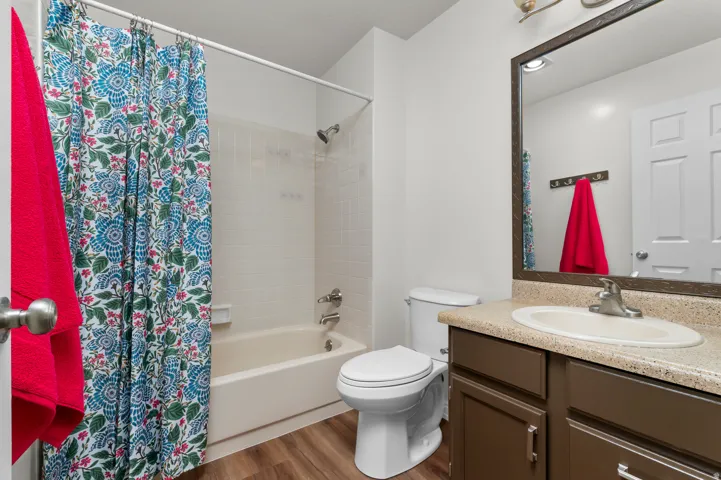 Bathroom featuring a built-in vanity with a stone-finish countertop, integrated sink, and an overhead mirror with task lighting