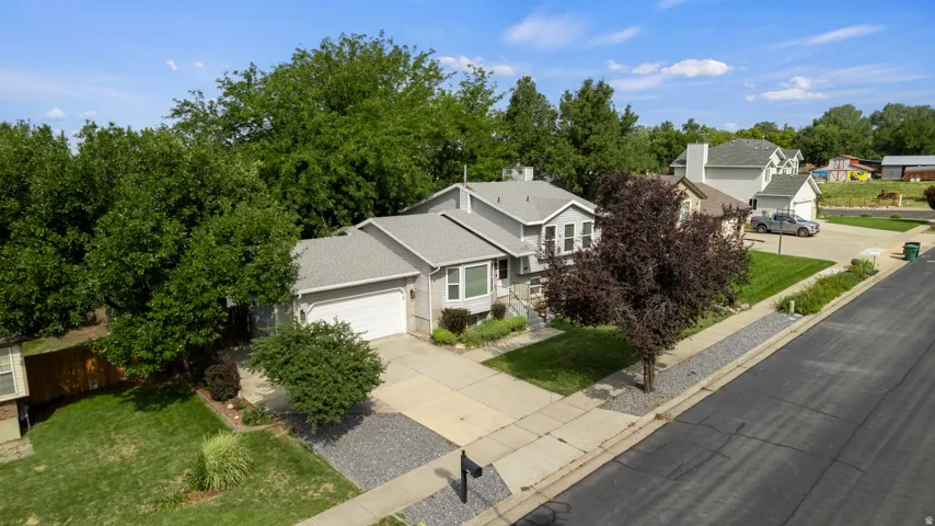 Single-family residence featuring a two-car garage, mature landscaping, and a paved driveway