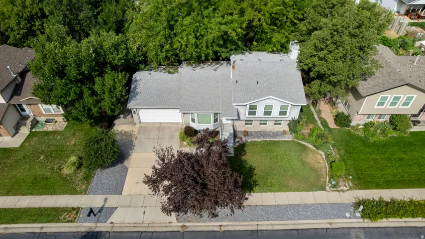 Asphalt shingle roof, attached garage, concrete driveway, and front lawn