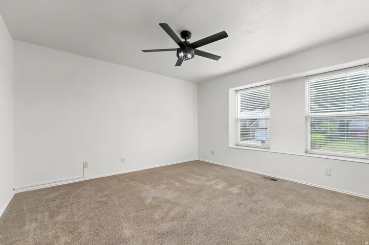 Neutral wall tones, dual windows with blinds, recessed window sills, and a ceiling fan