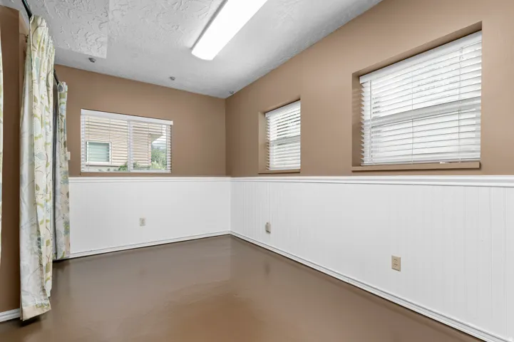 Three windows with horizontal blinds, white wainscoting, light brown walls, and a recessed ceiling light