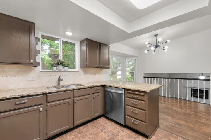 Kitchen featuring a stainless steel sink, built-in dishwasher, ample cabinetry, and granite countertops