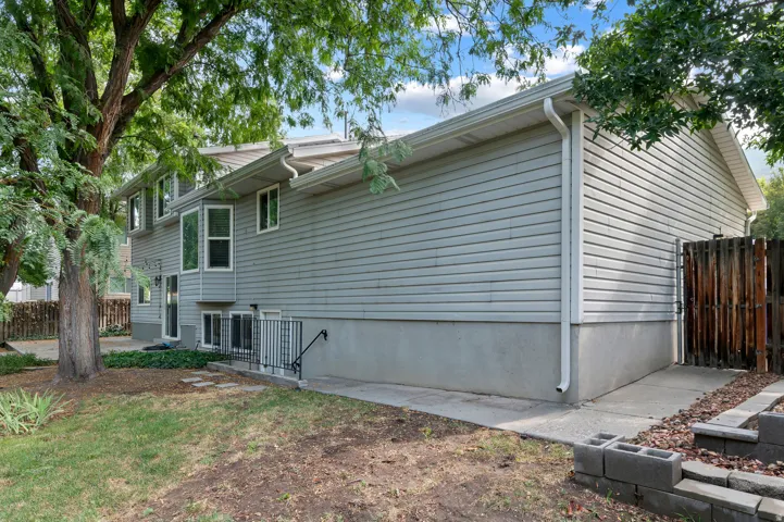 Gray horizontal siding with white trim, multiple bay windows, and a black metal handrail