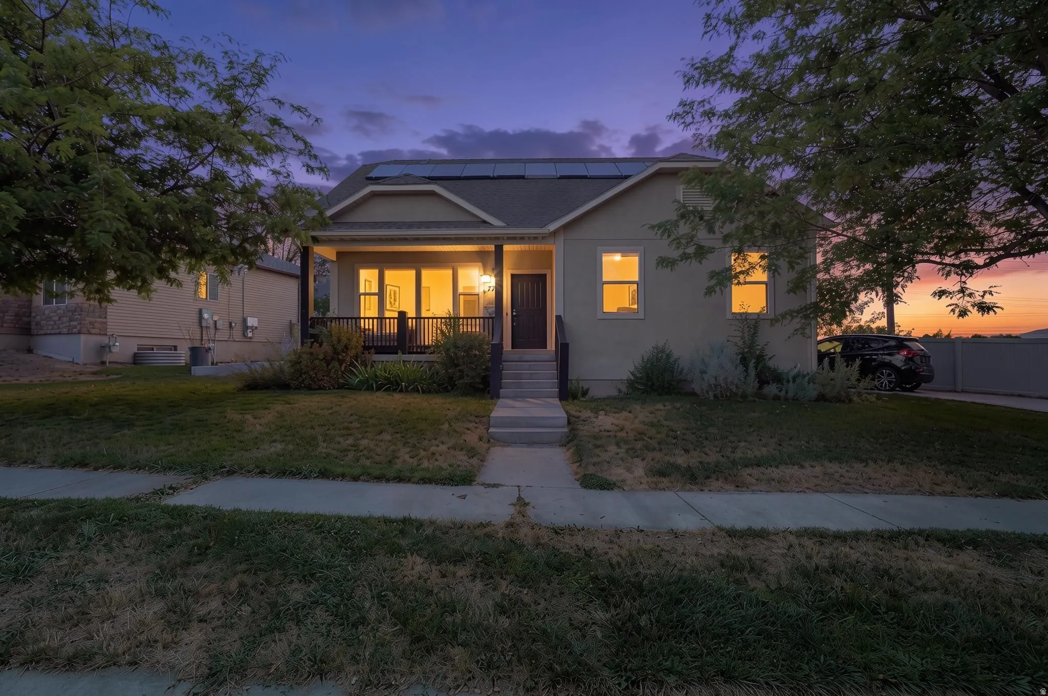 Front facade with a covered porch, solar panels, and a concrete pathway