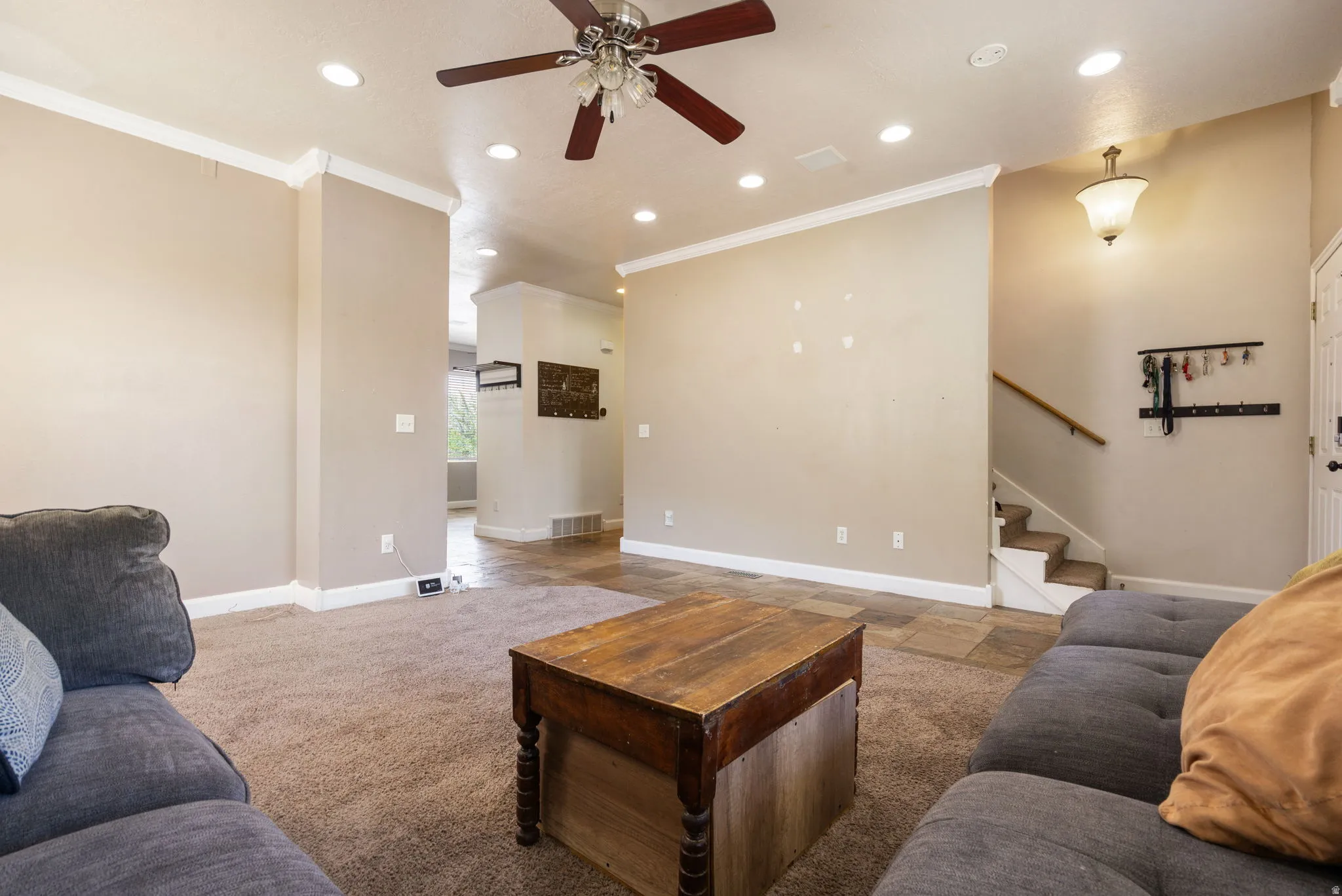 Recessed lighting, ceiling fan, crown molding, staircase with wood handrail, and tile flooring