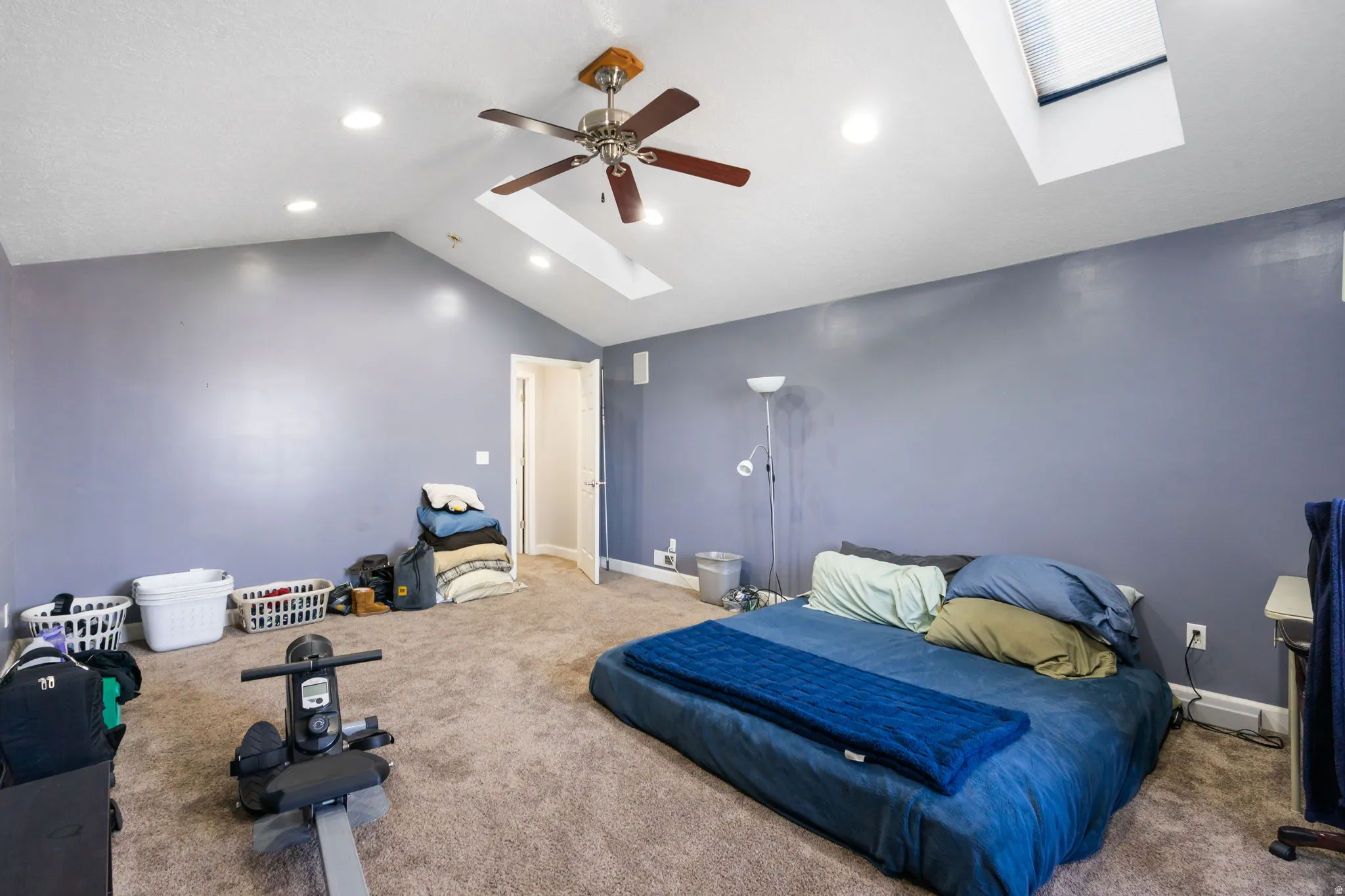 Vaulted ceiling with recessed lighting, skylight, ceiling fan, and carpeted flooring