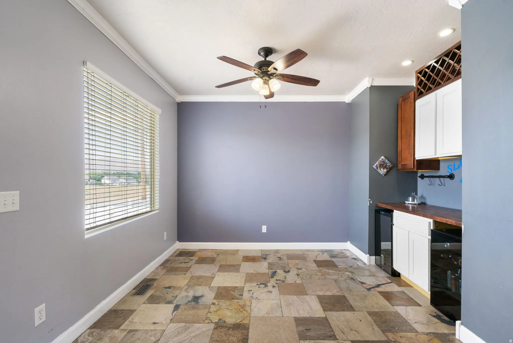 Tile flooring, ceiling fan with light fixture, built-in cabinetry, wood-finish countertop, and a window with blinds