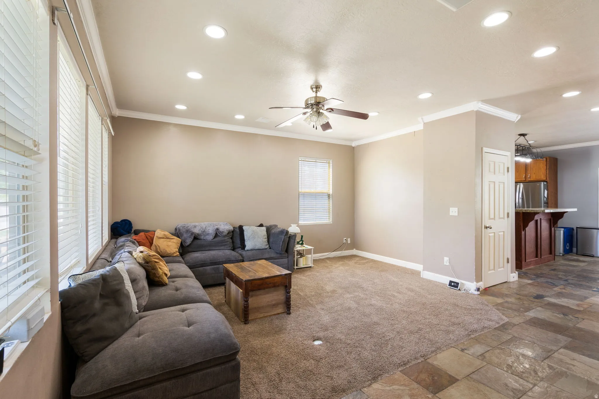 Recessed lighting, ceiling fan, crown molding, multiple windows with blinds, and durable tile flooring