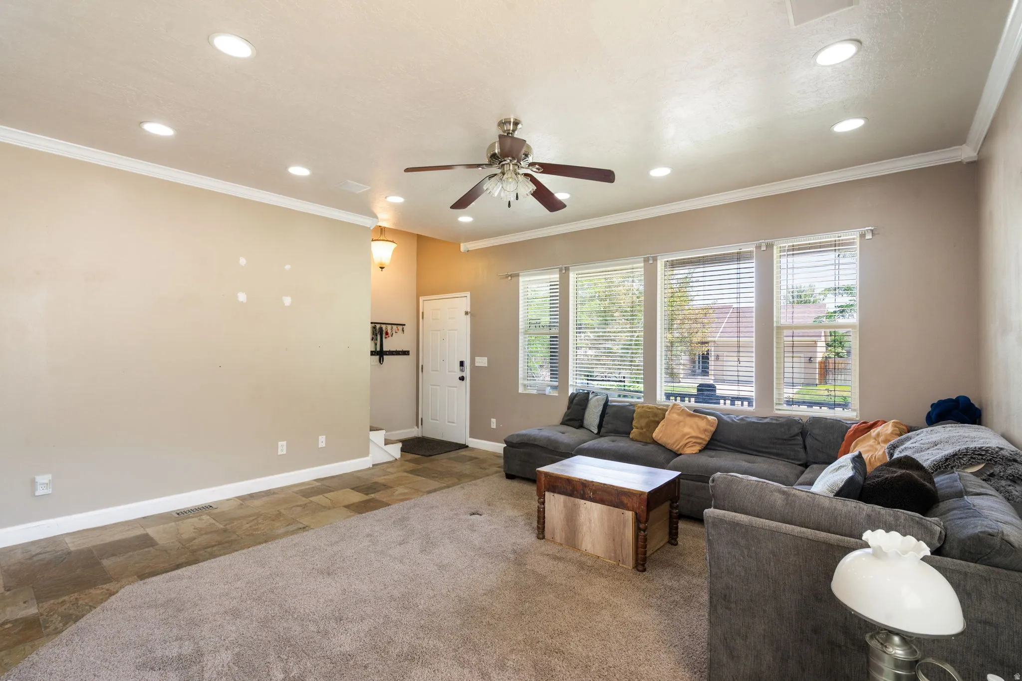 Recessed ceiling lighting, crown molding, multiple windows with blinds, a ceiling fan, and carpeted flooring