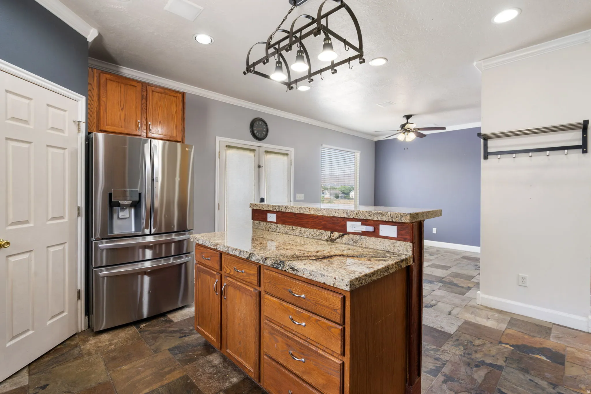Stainless steel French door refrigerator, wood-finish cabinetry, granite countertops, and recessed lighting