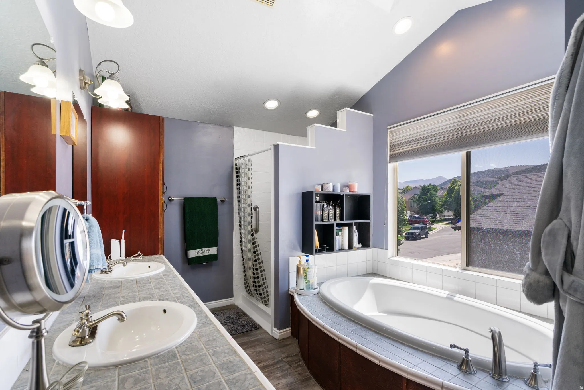 Double vanity with undermount sinks, walk-in shower, built-in soaking tub, and a large window