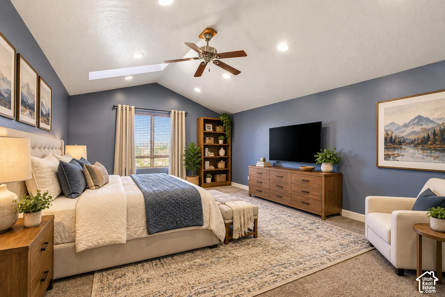 Vaulted ceilings featuring recessed lighting, a central ceiling fan, and a skylight, complemented by neutral carpeting
