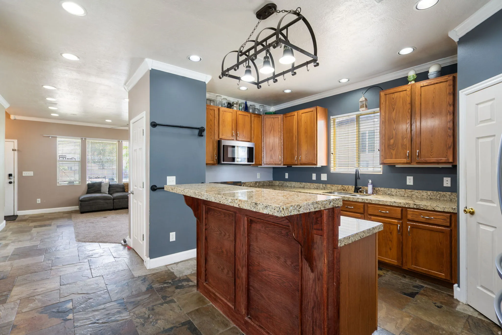 Kitchen featuring a granite-top island with wood paneling, recessed lighting, and a decorative iron light fixture