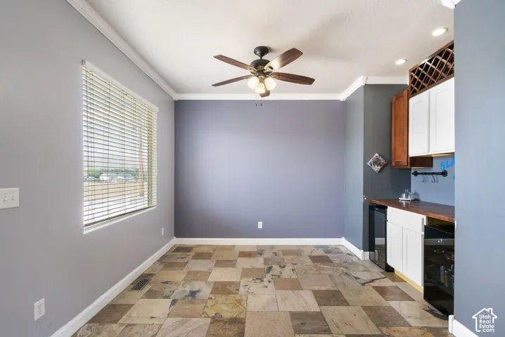 Tile flooring, ceiling fan with light fixture, built-in cabinetry, wood-finish countertop, and a window with blinds