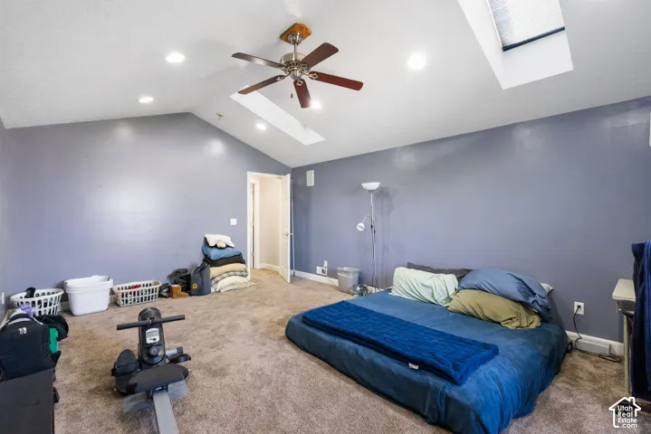 Vaulted ceiling with recessed lighting, skylight, ceiling fan, and carpeted flooring