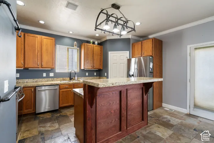 Kitchen featuring stone-look flooring, stainless steel appliances, wood cabinetry, granite countertops, and a central island with paneling