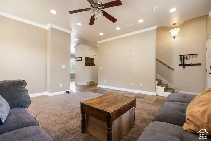 Recessed lighting, ceiling fan, crown molding, staircase with wood handrail, and tile flooring