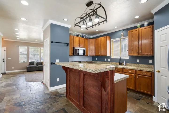 Kitchen featuring a granite-top island with wood paneling, recessed lighting, and a decorative iron light fixture