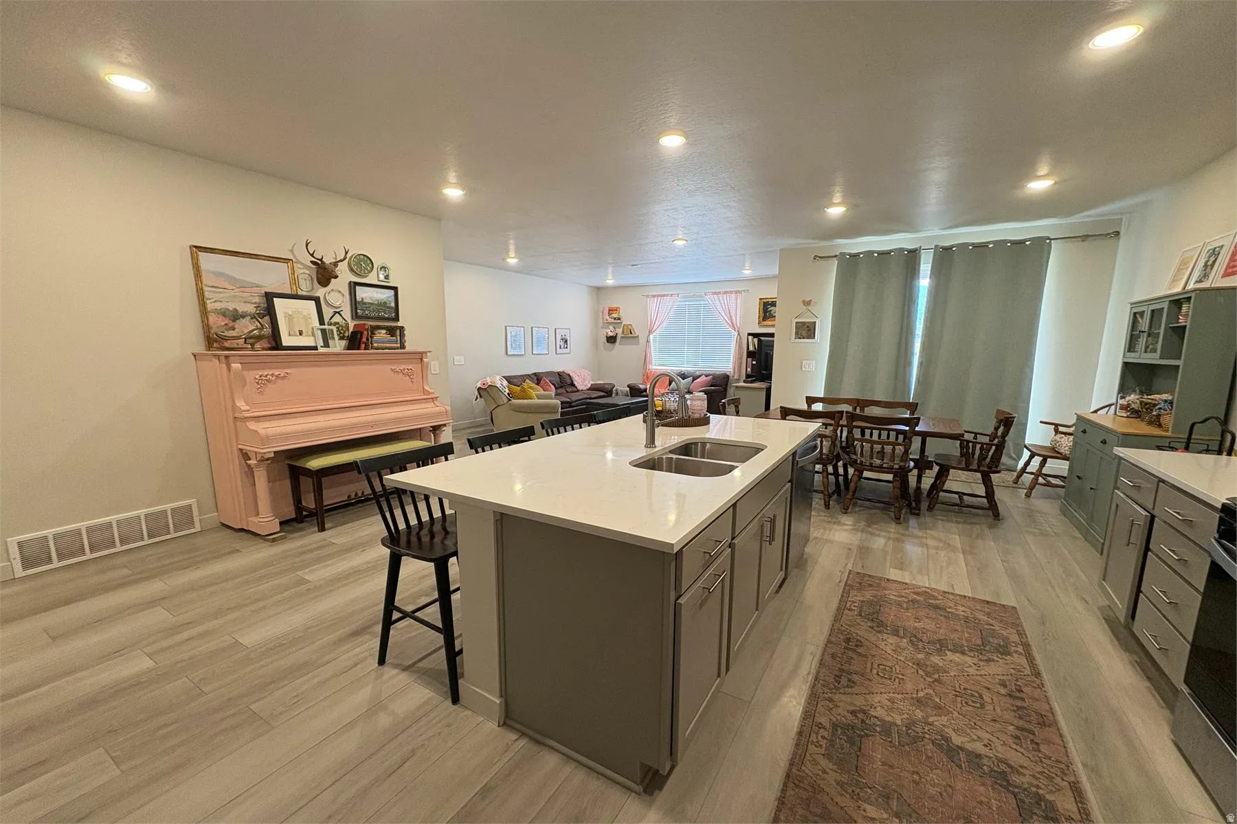 Recessed lighting, wood-finish flooring, kitchen island with dual sink and seating, contemporary cabinetry, and a dedicated dining area