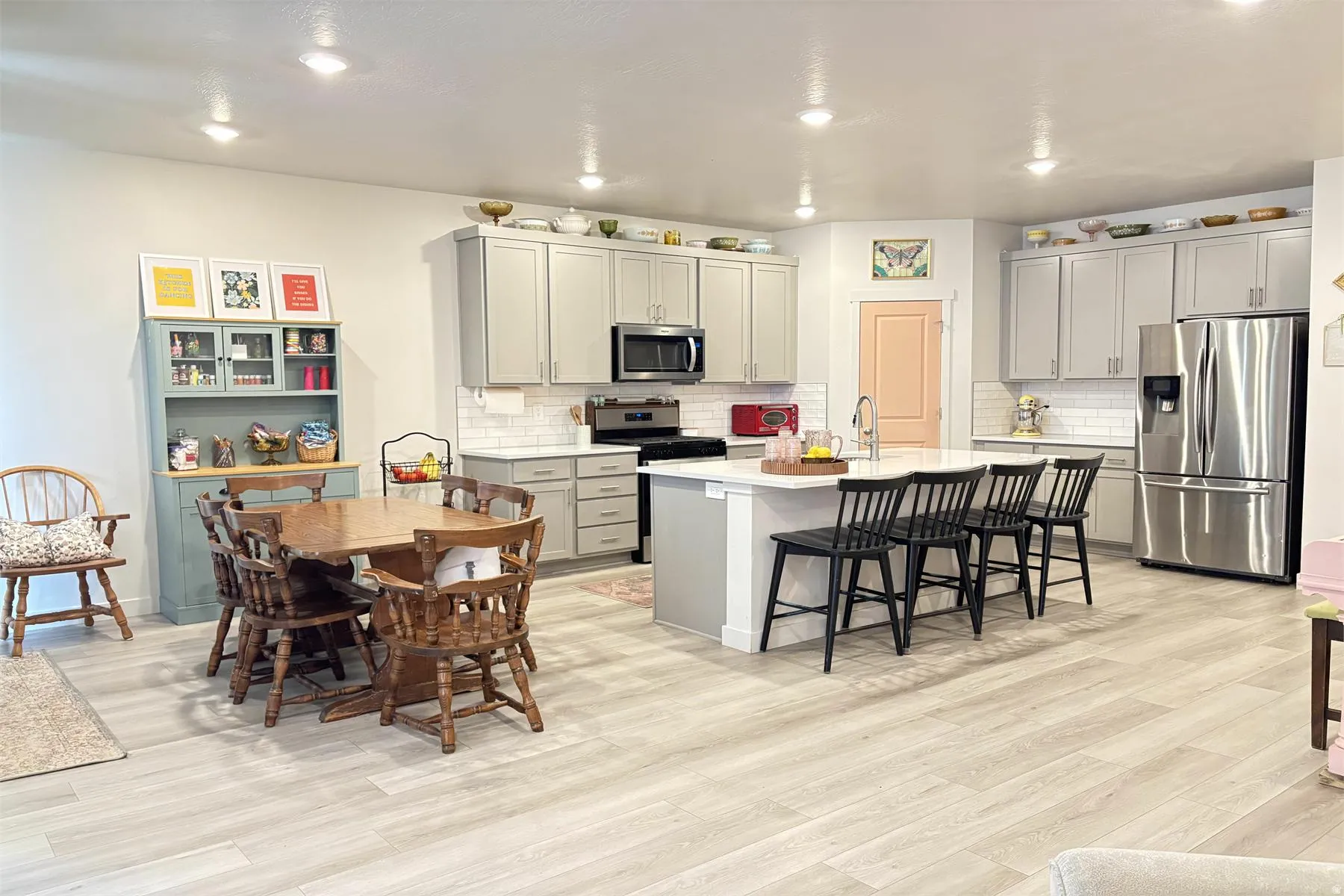 Open-concept kitchen and dining area featuring light-toned wood-finish flooring, recessed lighting, and a kitchen island with seating