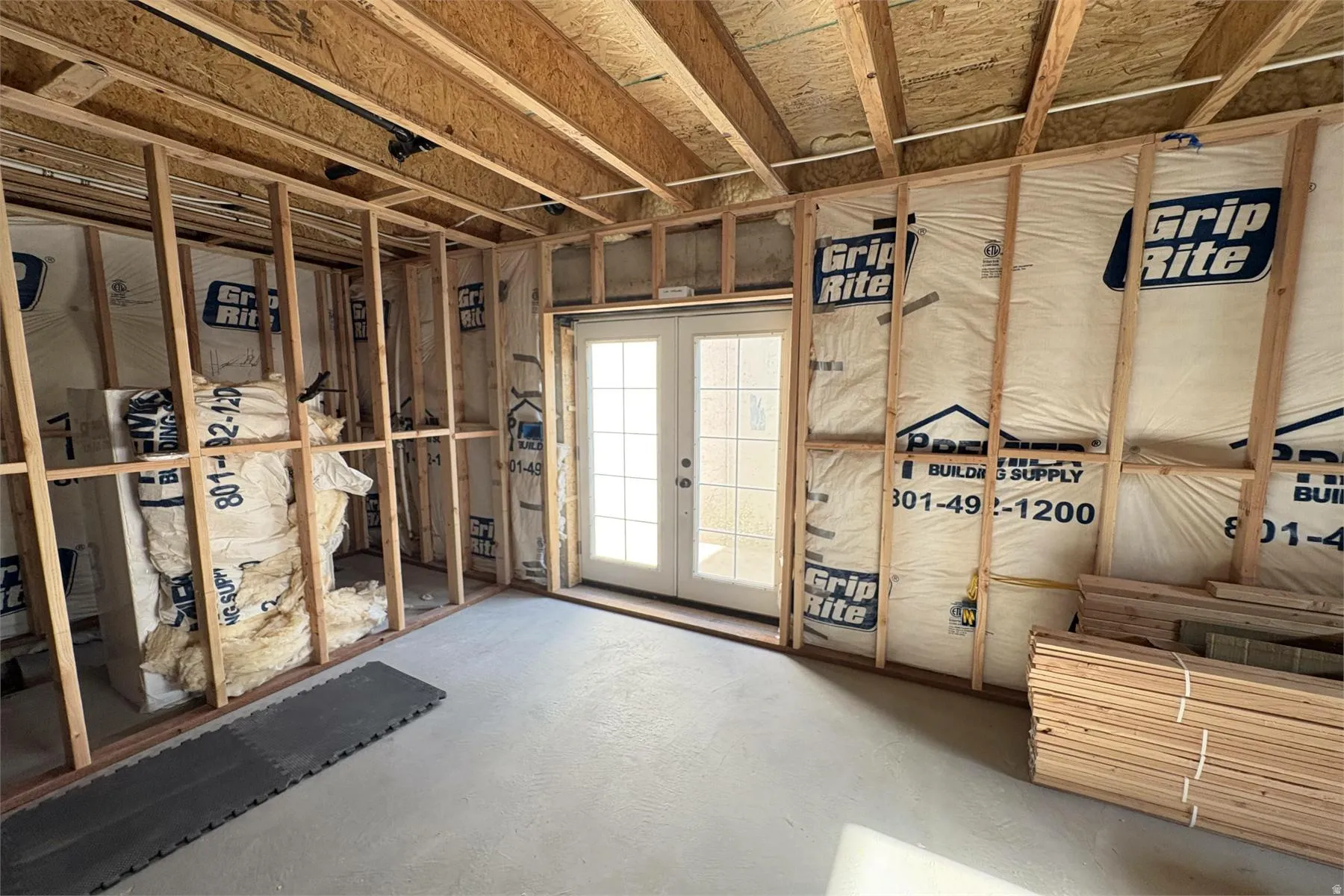 Framed interior space featuring exposed wood joists and a concrete floor