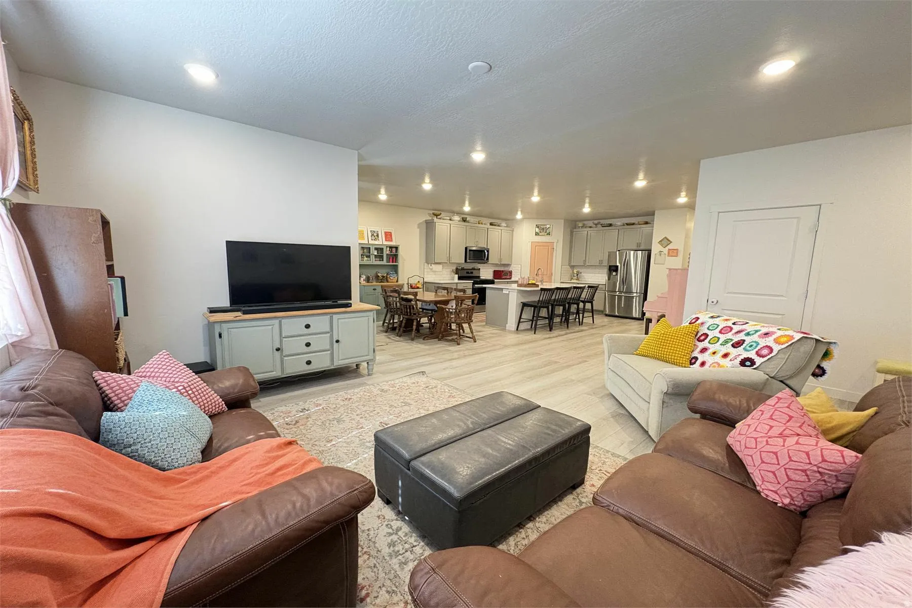 Open-concept living space featuring wood-finish flooring, recessed lighting, and a white interior door