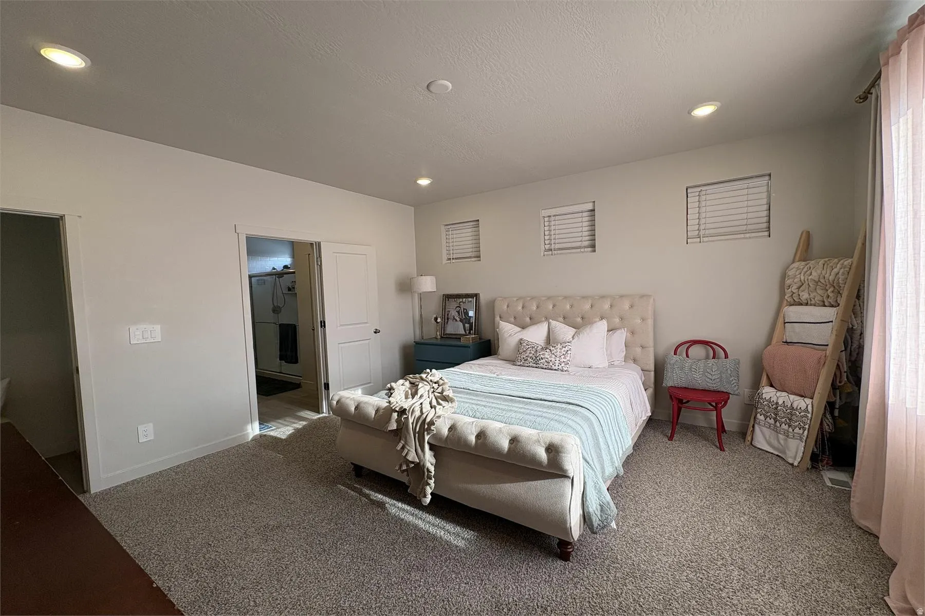 Recessed ceiling lighting, three windows with white blinds, light-toned carpeting, white interior doors, and a neutral wall color