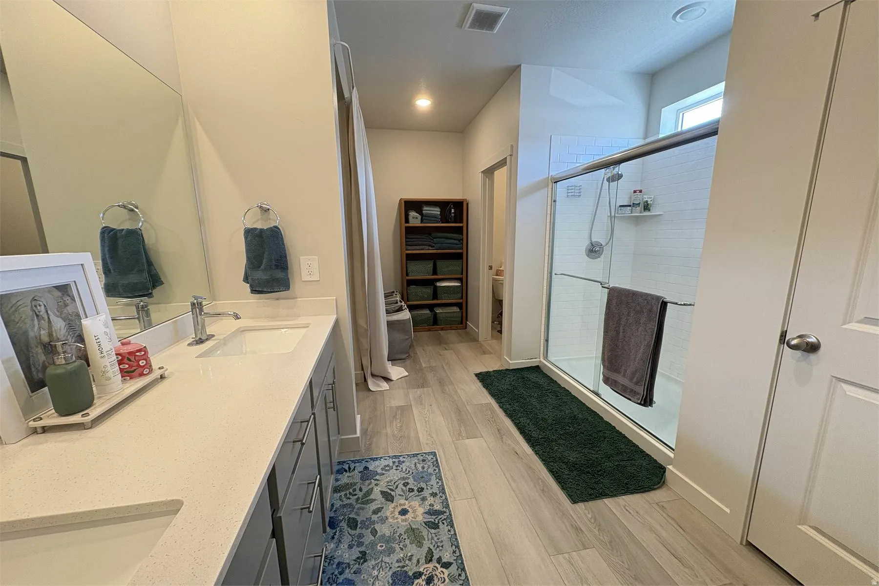 Dual vanity with undermount sinks, light-toned countertops, and wood-finish flooring
