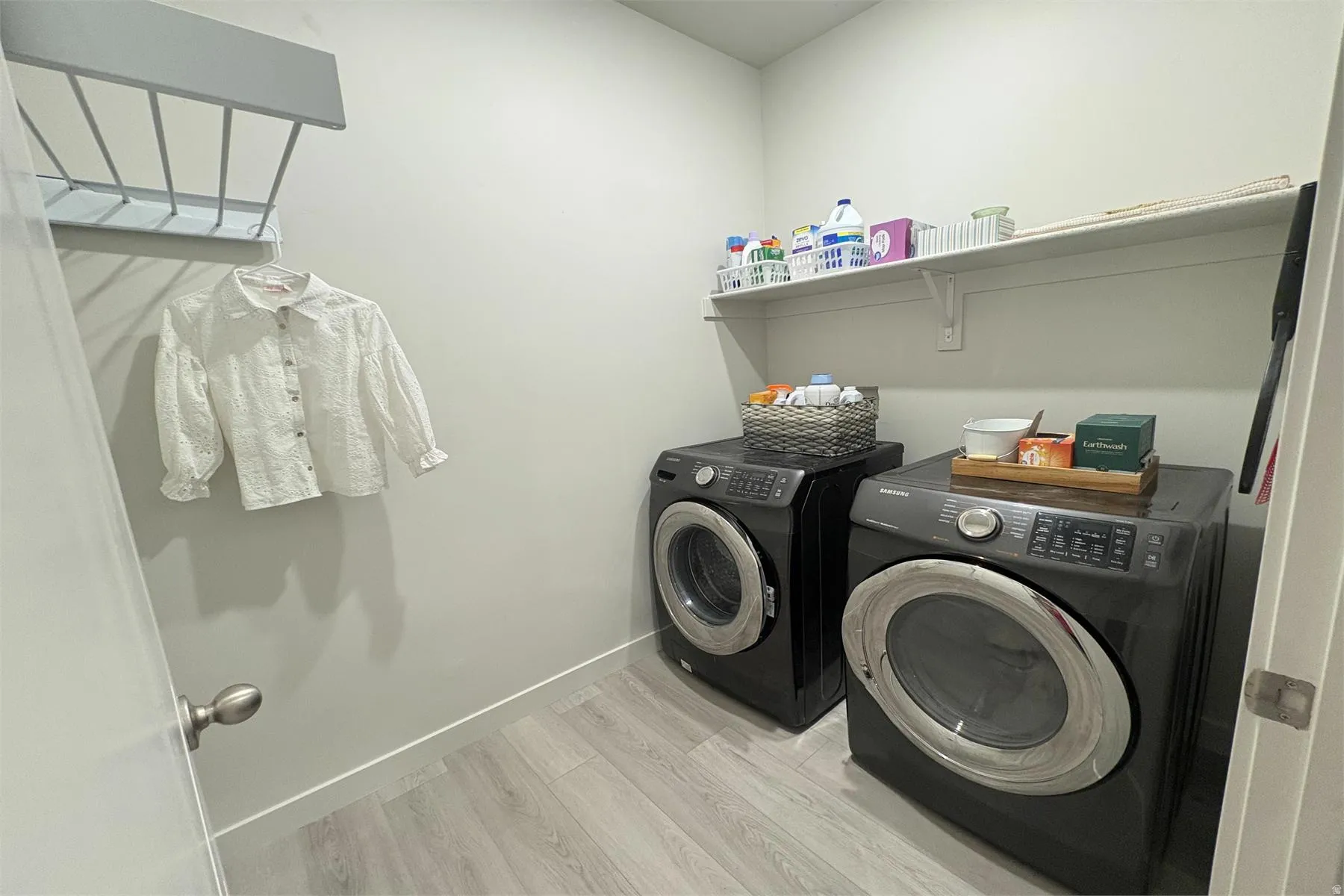 Laundry area featuring wood-finish flooring, a wall-mounted drying rack, and built-in shelving