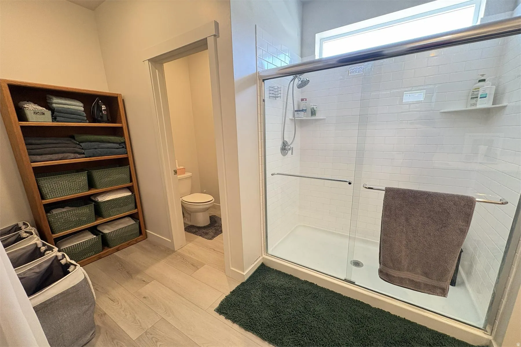 Glass-enclosed shower with white subway tile surround, integrated shelving, and a rain showerhead