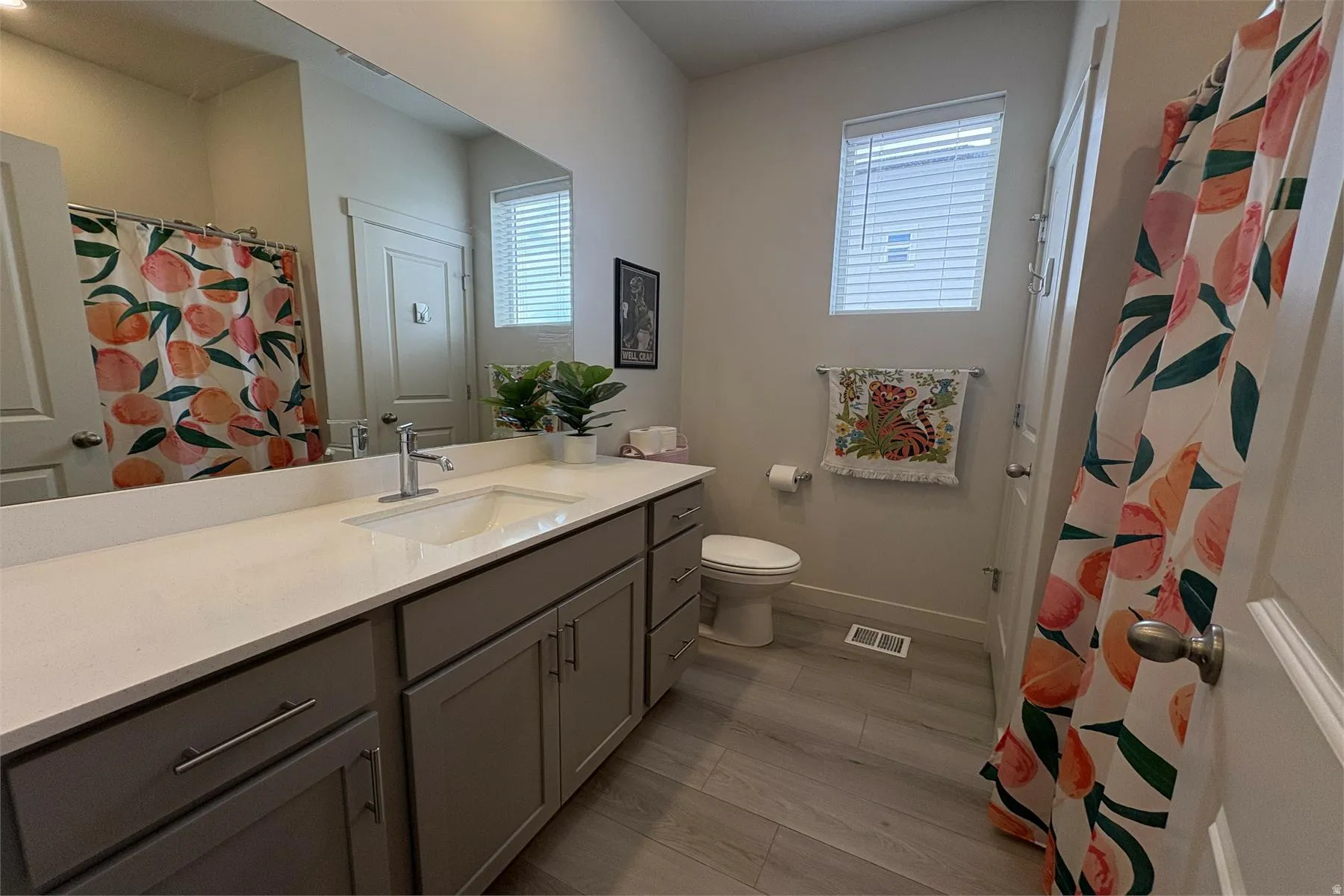 Expansive vanity featuring a single basin sink, white countertop, and gray cabinetry with brushed nickel hardware