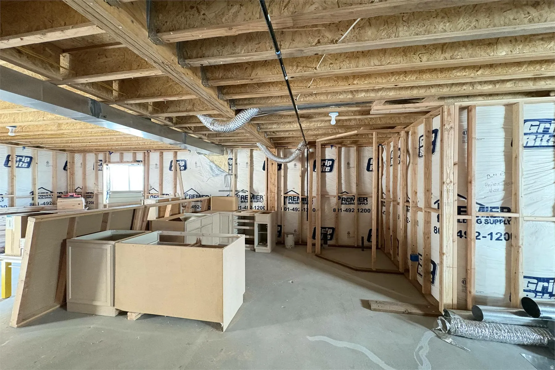 Unfinished interior space featuring wood framing, exposed ceiling joists, and pre-installed base cabinetry
