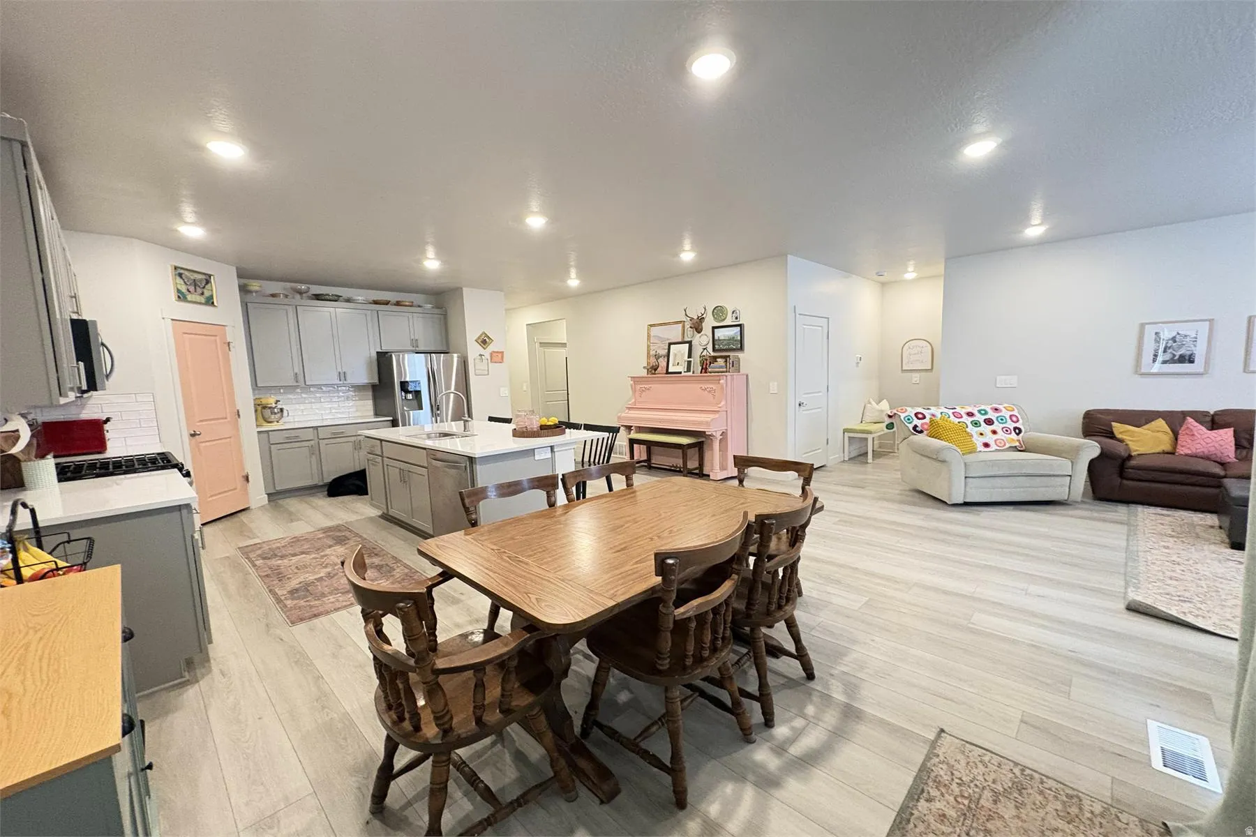 Spacious open-concept living area featuring light wood-finish flooring, recessed lighting, and a kitchen with light-toned cabinetry and a center island