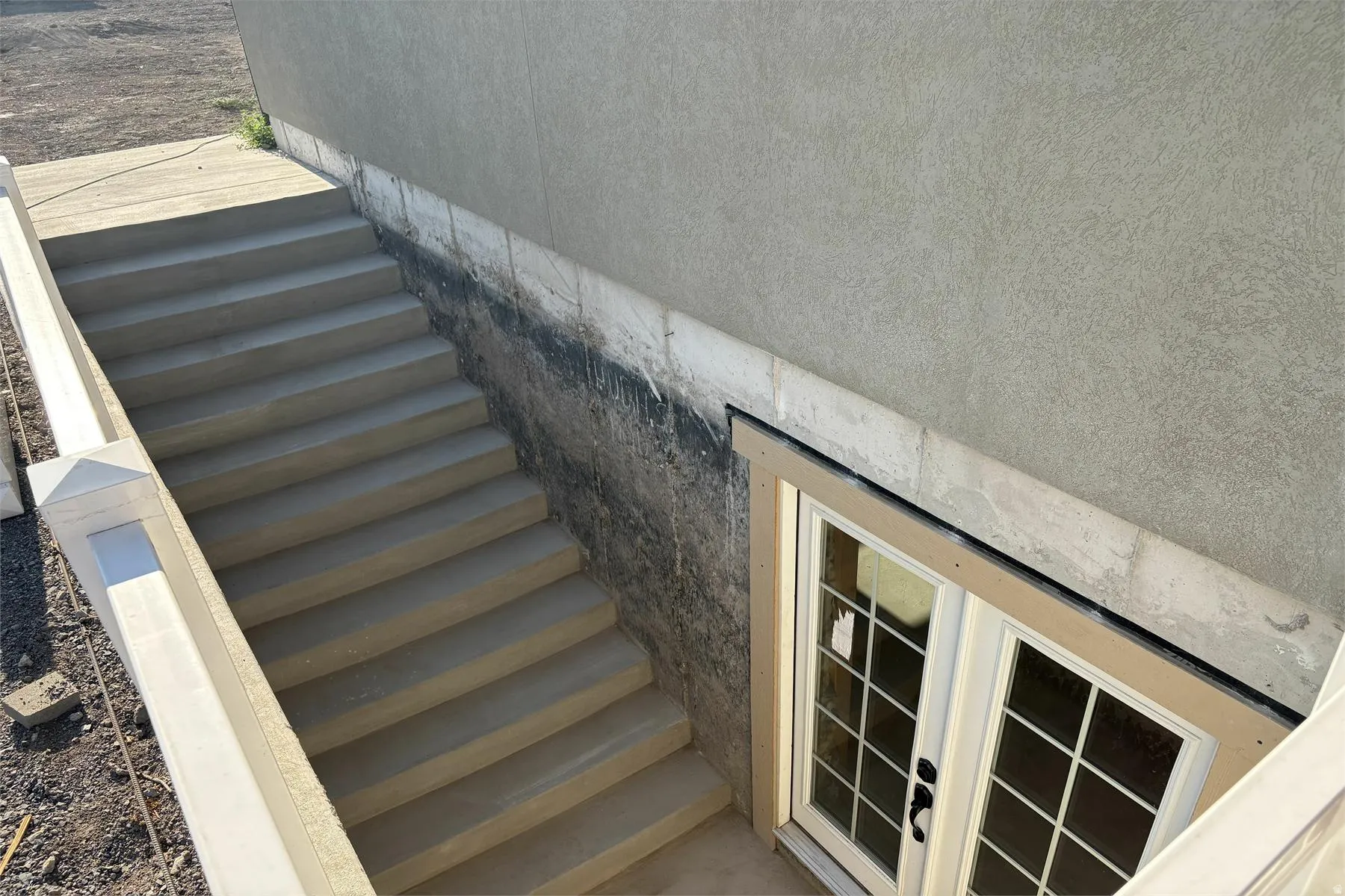Concrete exterior stairs leading to double pane French doors