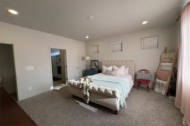 Recessed ceiling lighting, three windows with white blinds, light-toned carpeting, white interior doors, and a neutral wall color