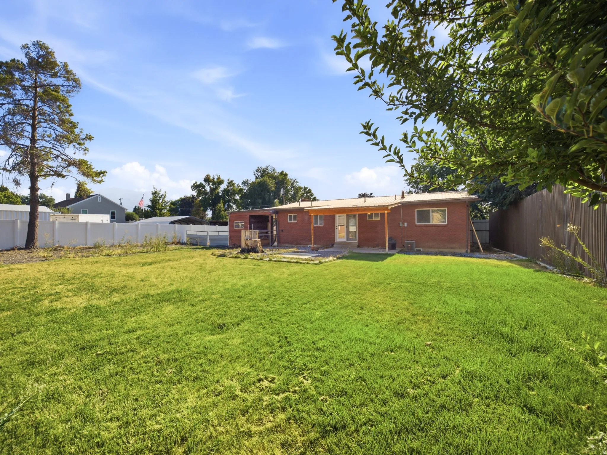 Full sprinklers in the backyard. Expansive backyard featuring a lawn, privacy fencing, and a red brick exterior