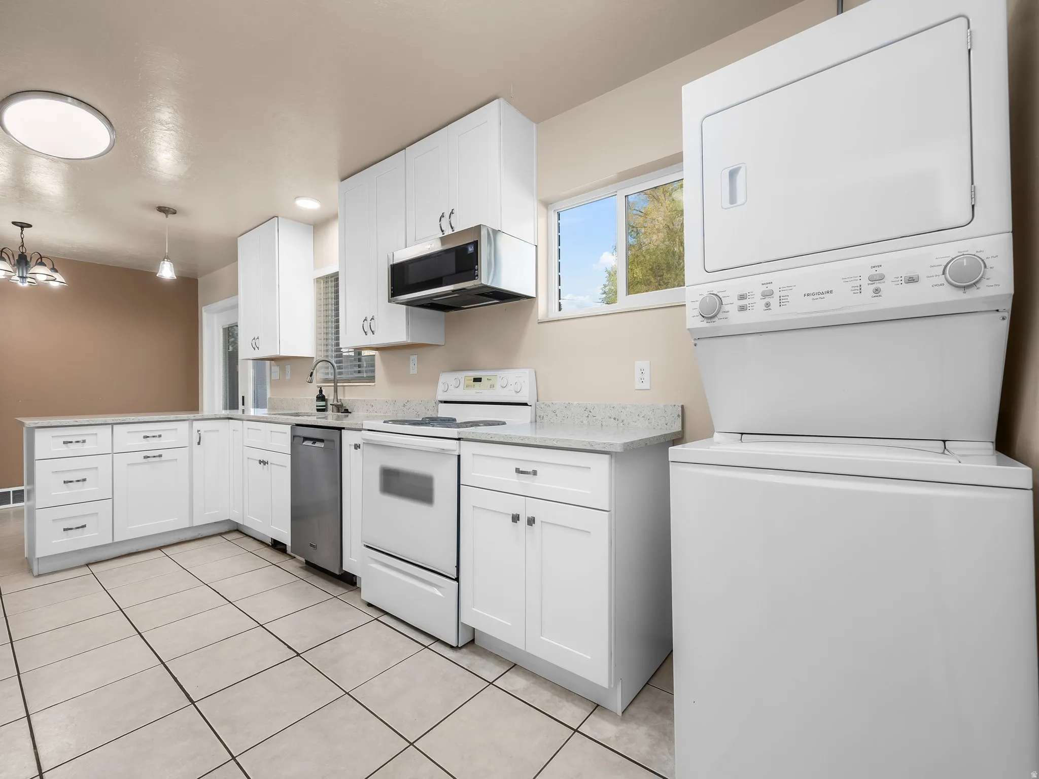 White cabinetry, light-toned tile flooring, and integrated white appliances