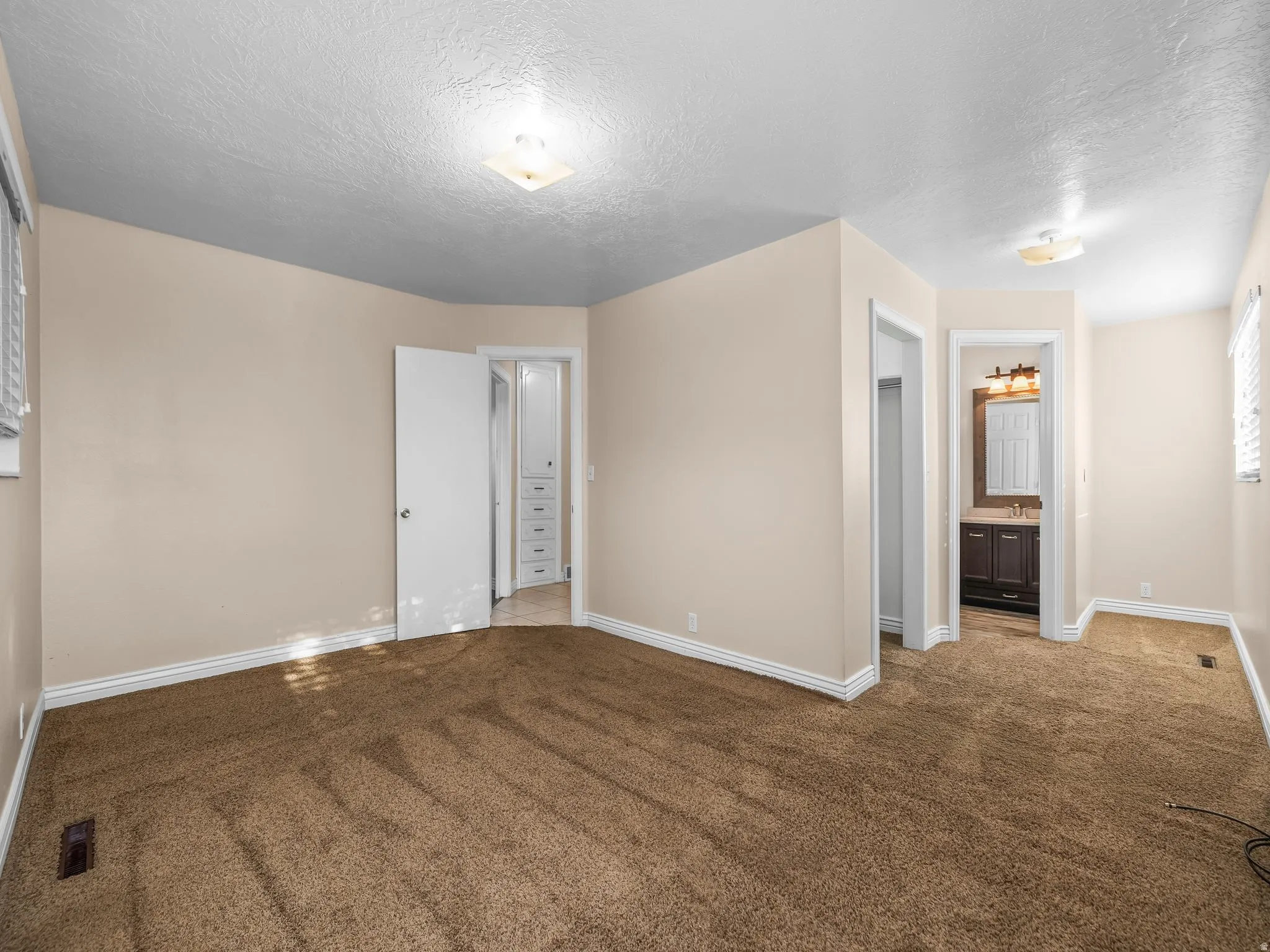 Primary bedroom. Plush carpet flooring, neutral wall tones, and recessed lighting