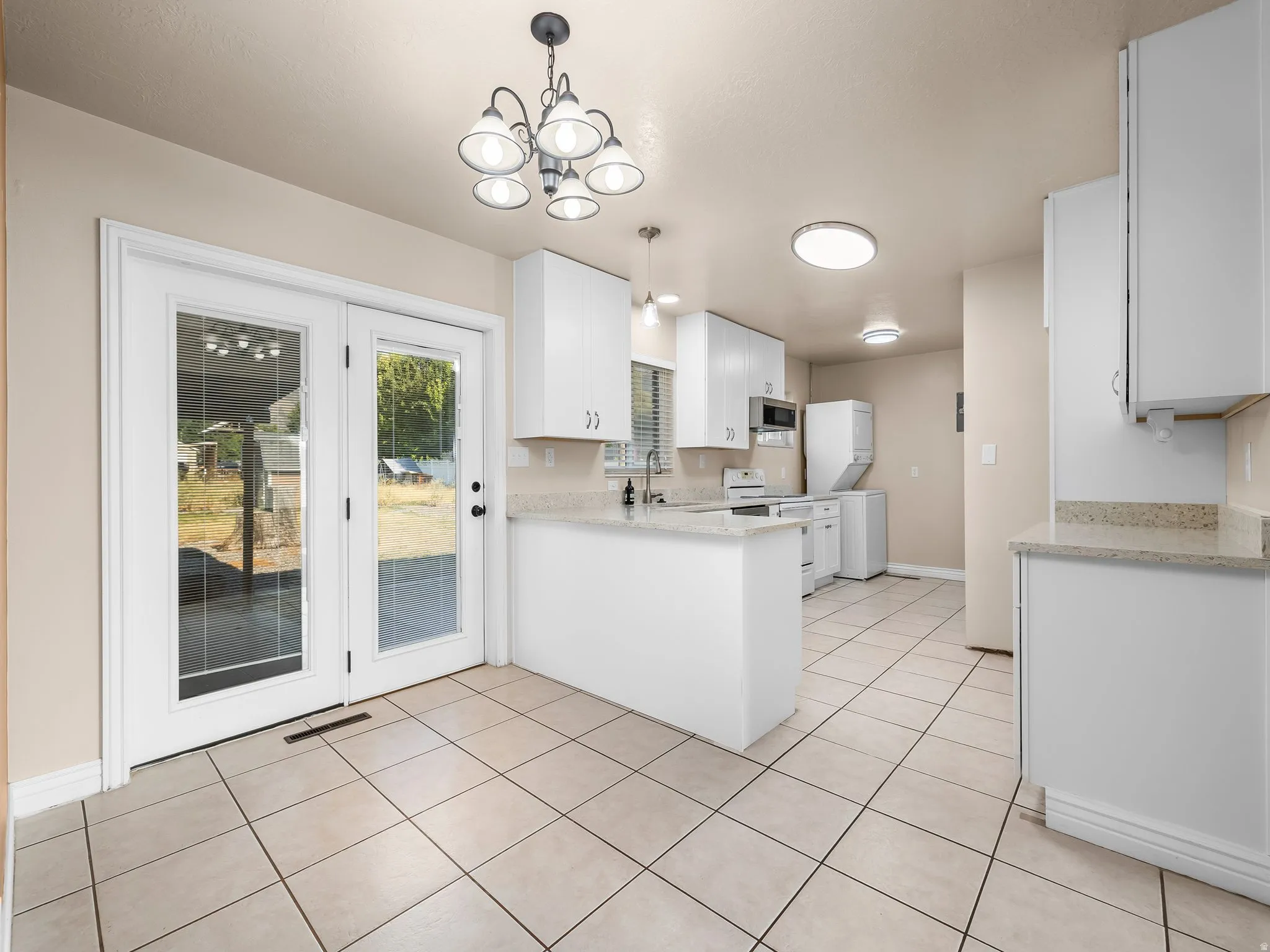 Kitchen featuring tile flooring, white cabinetry, light-toned countertops, and French doors