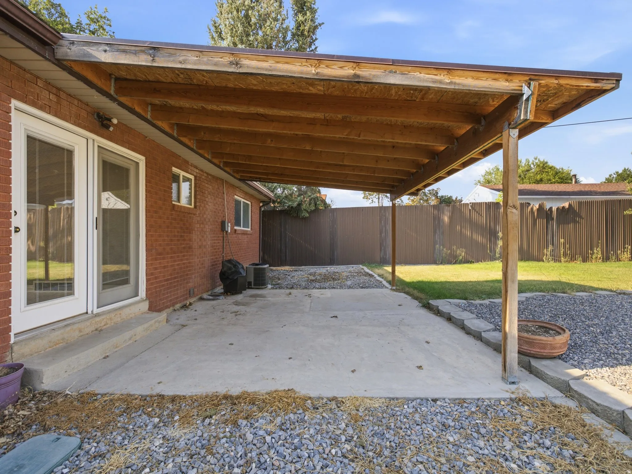 Patio off the kitchen. Expansive covered patio with exposed wood beams, brick exterior, and a concrete patio surface