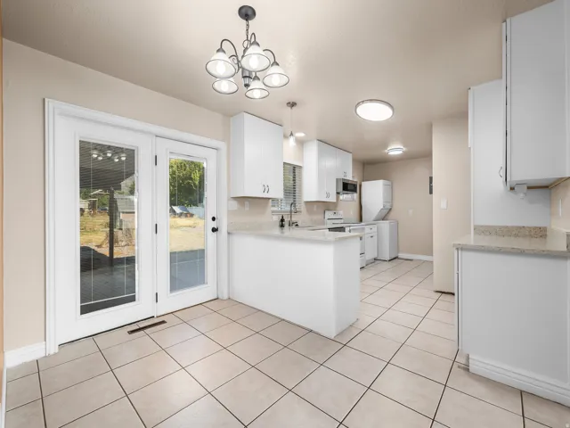 Kitchen featuring tile flooring, white cabinetry, light-toned countertops, and French doors