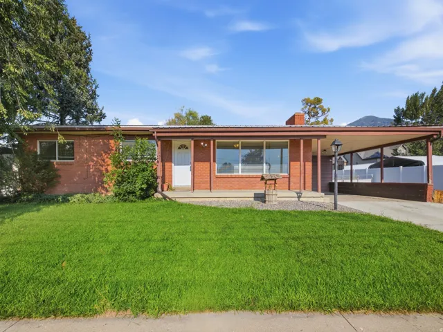 Brick exterior with a covered front porch and an attached carport all covered with a metal roof