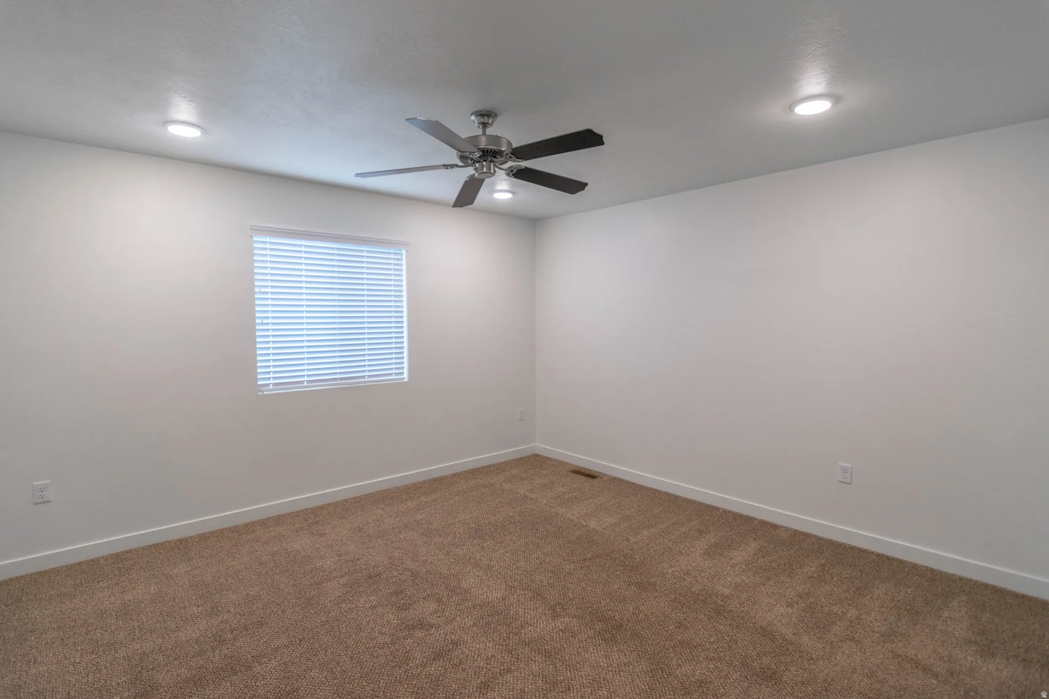 Spacious room featuring neutral carpet flooring, a ceiling fan with light fixture, and recessed lighting