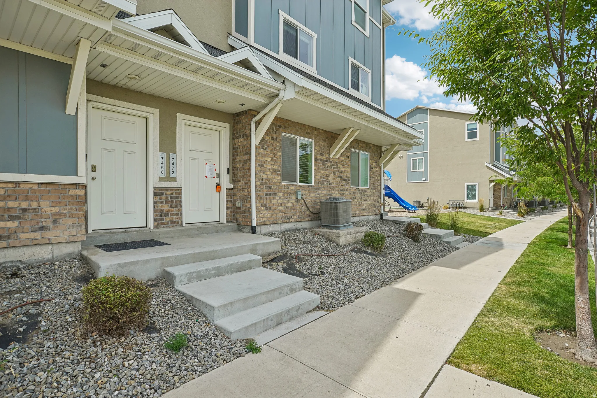 Modern townhome exterior featuring light brick, blue siding, and white trim