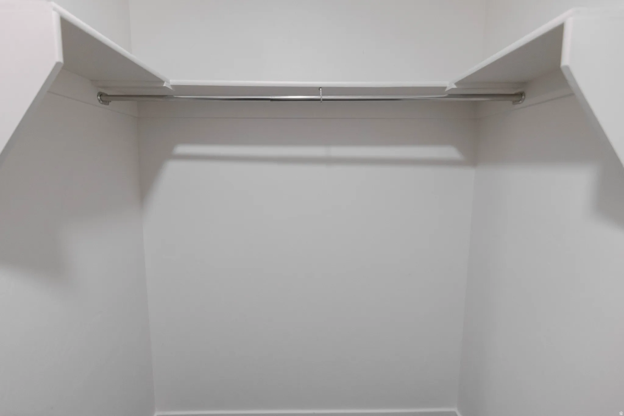 White-painted closet interior with an integrated upper shelf and a chrome hanging rod