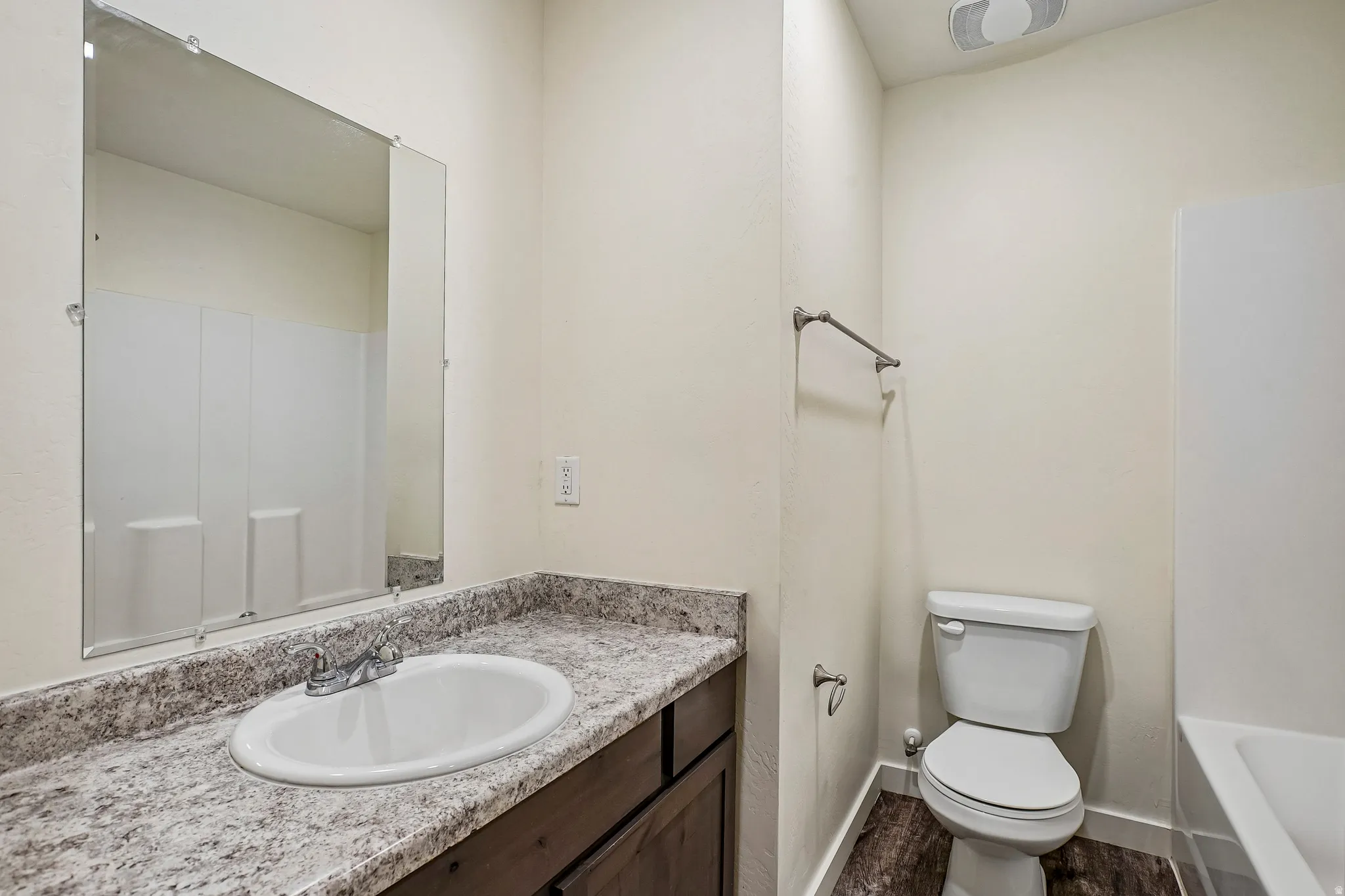 Bathroom vanity with an oval undermount sink and chrome faucet, set on a speckled countertop