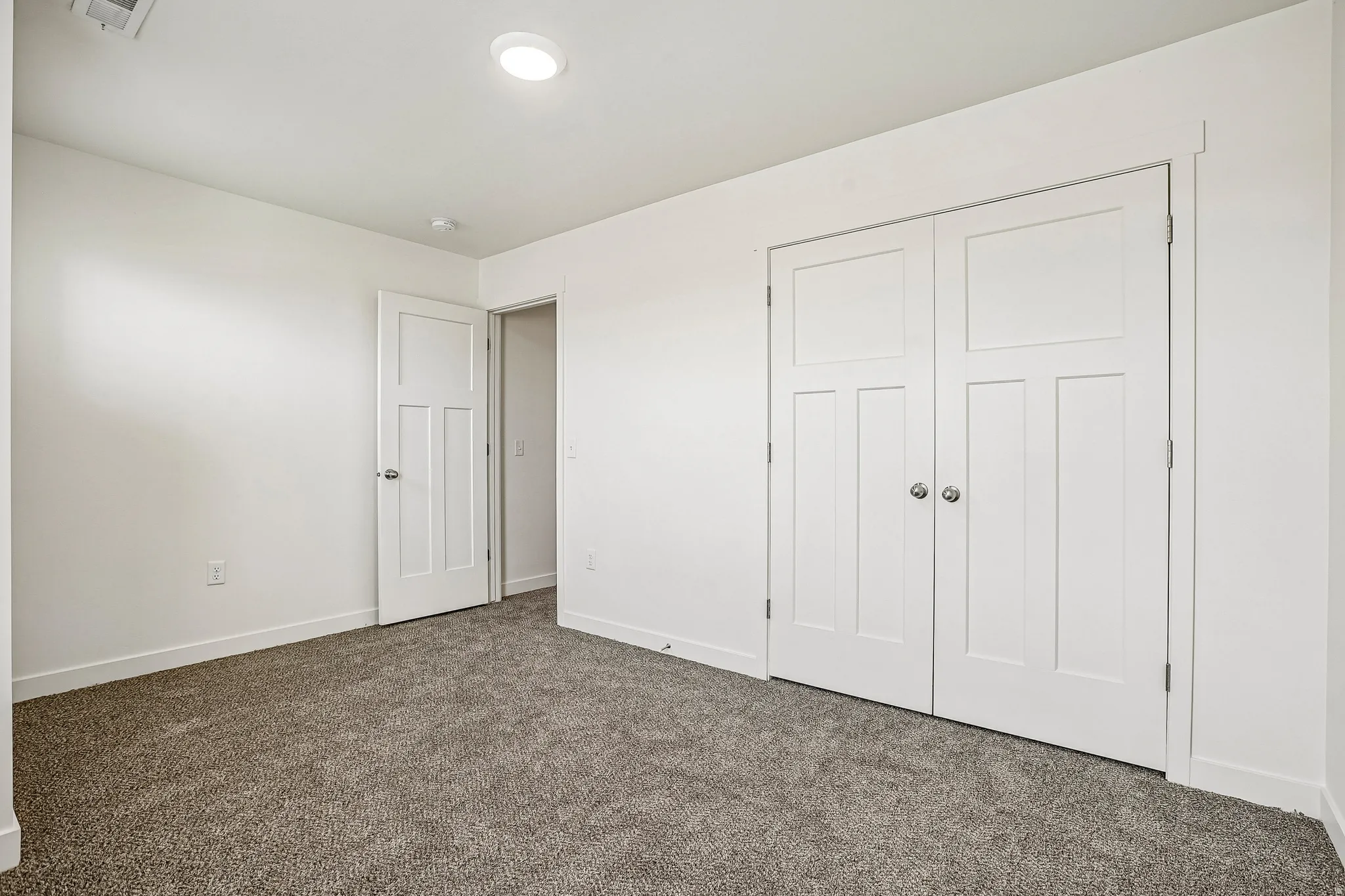 Neutral-toned room featuring a soft gray carpet, white walls, and a recessed ceiling light