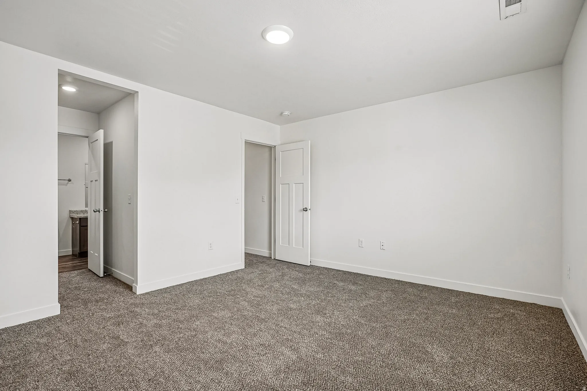 Spacious room featuring neutral carpeting, white walls, and a flush-mounted ceiling light