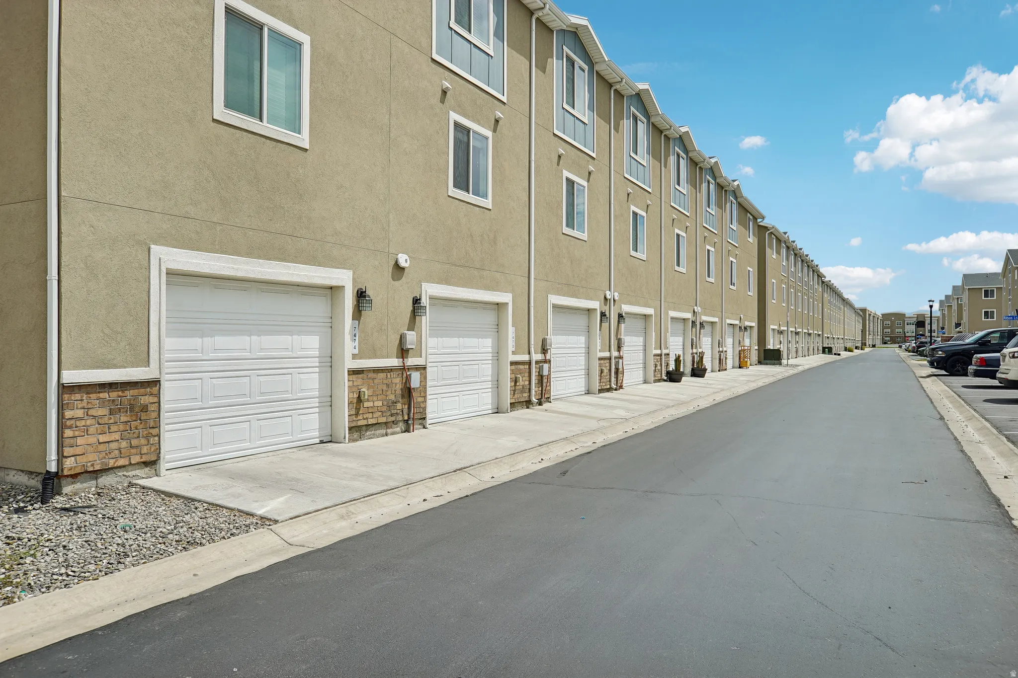 Exterior featuring stucco siding, stone accents, white garage doors, and individual concrete driveways